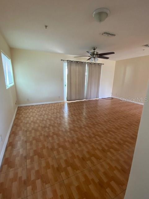 An empty room features light-colored walls, wood-look tile flooring, a ceiling fan, and sliding doors — 3131 LITTLE SOUND DRIVE, ORLANDO, FL