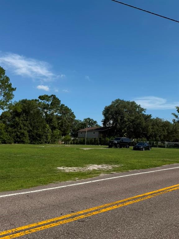 A grassy vacant lot sits beside a paved road with two parked vehicles in the distance — 8844 S MOBLEY ROAD, TAMPA, FL