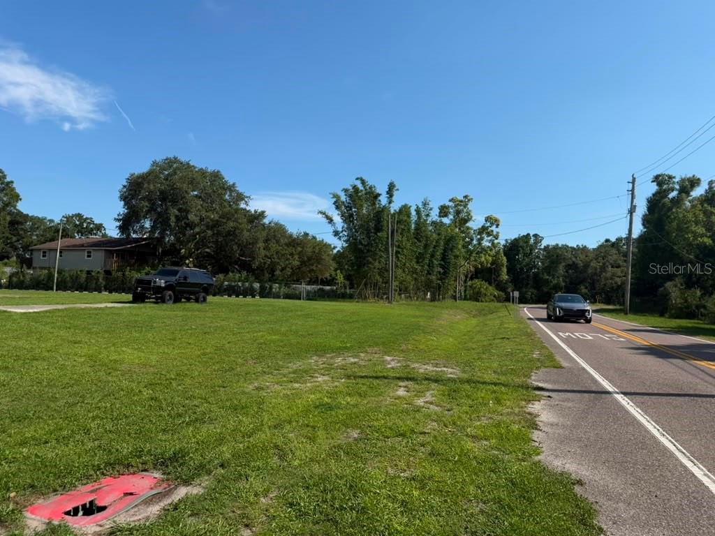A grassy vacant lot sits next to a paved road with a car driving by — 8844 S MOBLEY ROAD, TAMPA, FL