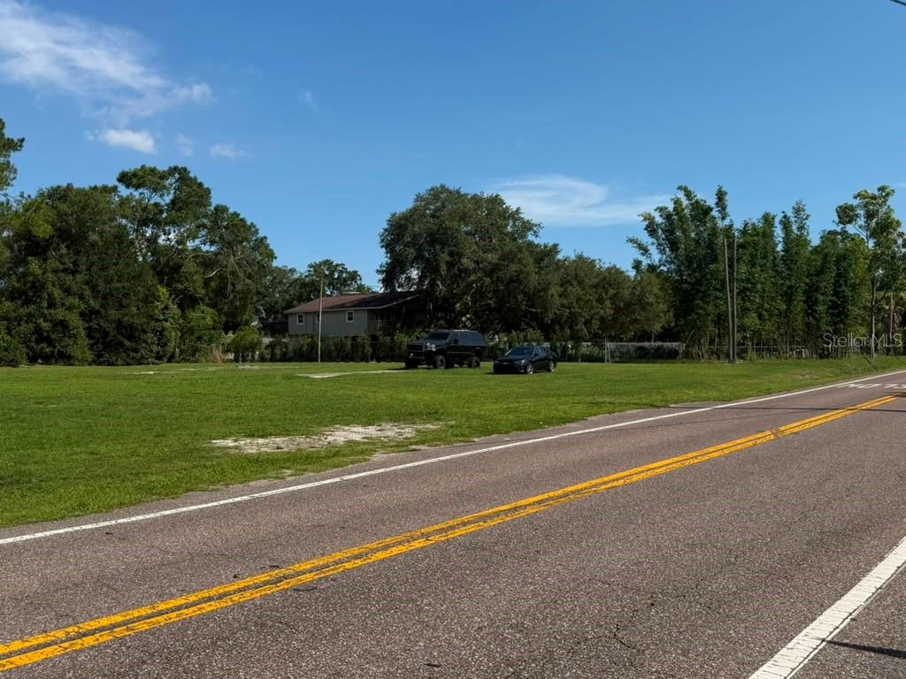 A grassy, vacant lot sits beside a paved road with two parked vehicles — 8844 S MOBLEY ROAD, TAMPA, FL