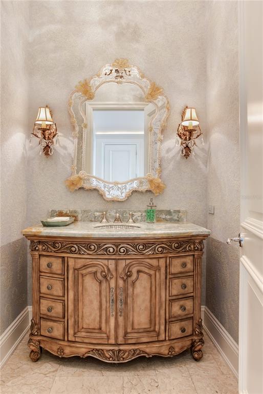 A powder room features a decorative ornate mirror, wall sconces, and a carved wooden vanity — 52 LADOGA AVENUE, TAMPA, FL