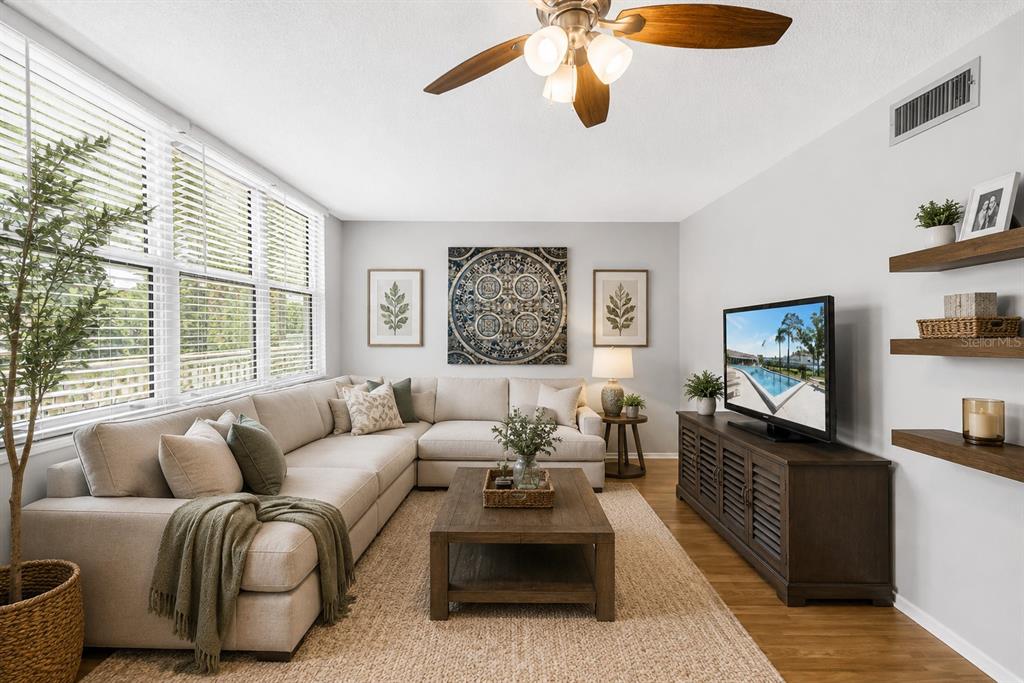 A living room features a beige sectional sofa, a wooden coffee table, and a television — 4720 LOCUST STREET NE UNIT 318, ST PETERSBURG, FL