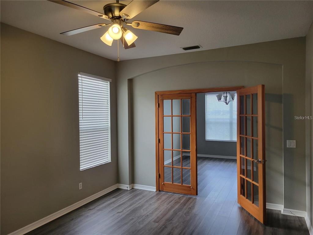 A room with gray walls, wood-look flooring, a ceiling fan, and French doors — 7215 COLONIAL LAKE DRIVE, RIVERVIEW, FL