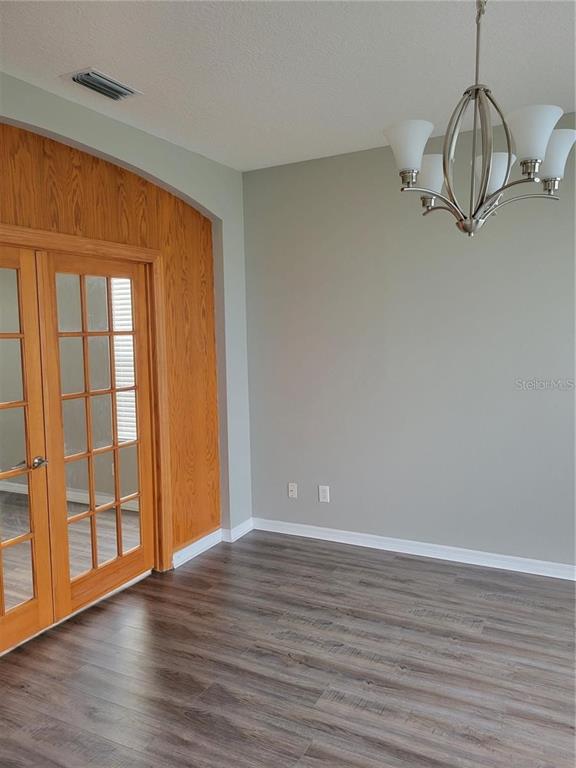 A room with gray walls, wood-look flooring, a chandelier, and wood-framed French doors — 7215 COLONIAL LAKE DRIVE, RIVERVIEW, FL