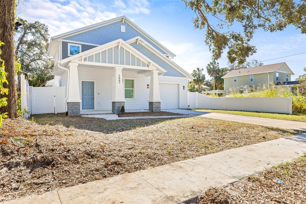 A light blue two-story house with a covered front porch and a white vinyl fence — 3005 E 17TH AVENUE, TAMPA, FL