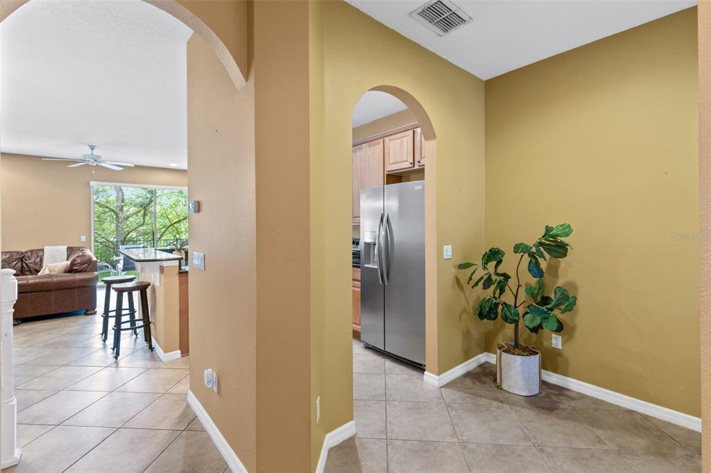 A view through an arched doorway shows a kitchen with stainless steel appliances and tile — 5128 CYPRESS BRANCH POINT, OVIEDO, FL