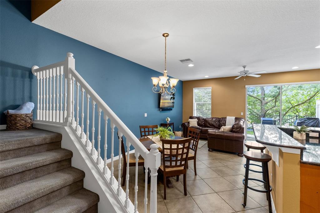 A view from the stairs looking into a dining area and living room with tile floors — 5128 CYPRESS BRANCH POINT, OVIEDO, FL