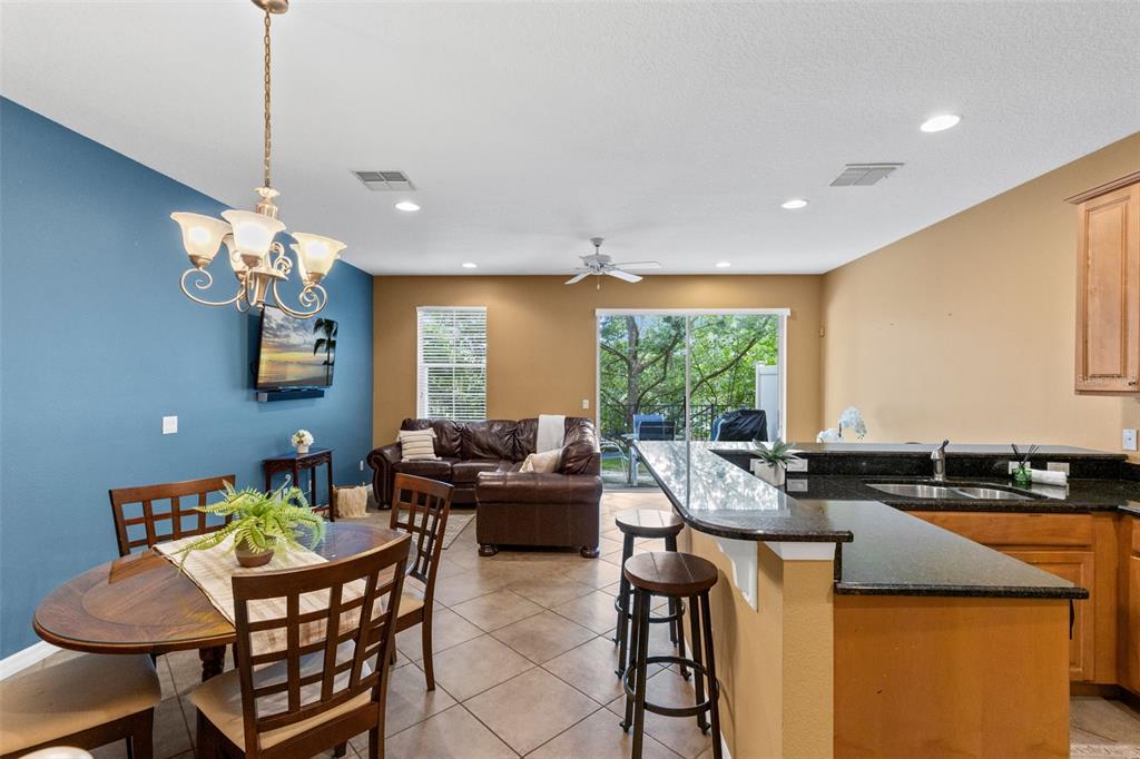 An open-concept living and dining area features tile floors, a kitchen island, and blue walls — 5128 CYPRESS BRANCH POINT, OVIEDO, FL