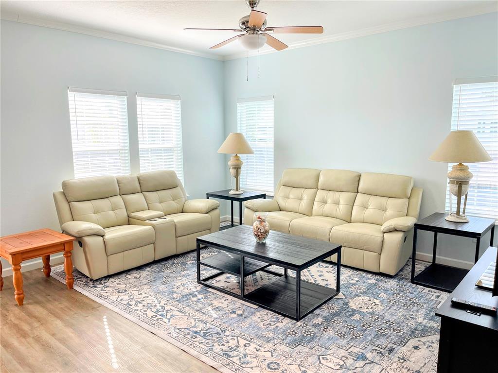 A living room features two cream-colored leather sofas, a dark coffee table, and area rug — 612 CAREFREE, VENICE, FL