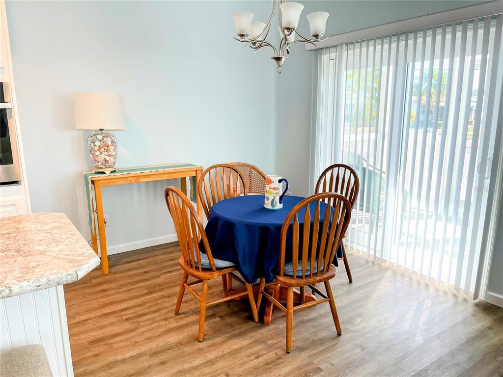 A dining area features a round table with four chairs, a console table, and vertical blinds — 612 CAREFREE, VENICE, FL