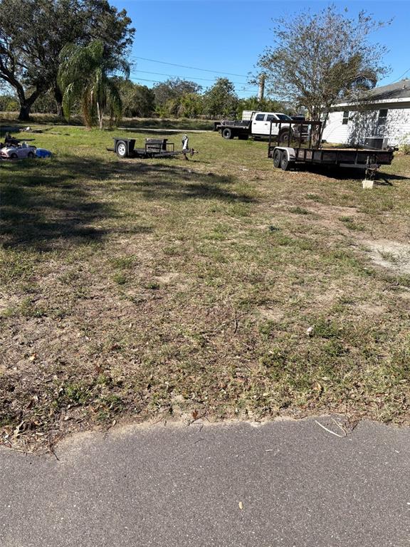 A grassy lot features two utility trailers, a white pickup truck, and a small house — 811 NORTH AVENUE, FROSTPROOF, FL