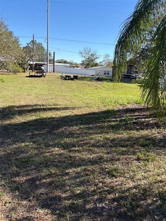 A grassy, open lot features a utility trailer and a small shed under a clear sky — 811 NORTH AVENUE, FROSTPROOF, FL