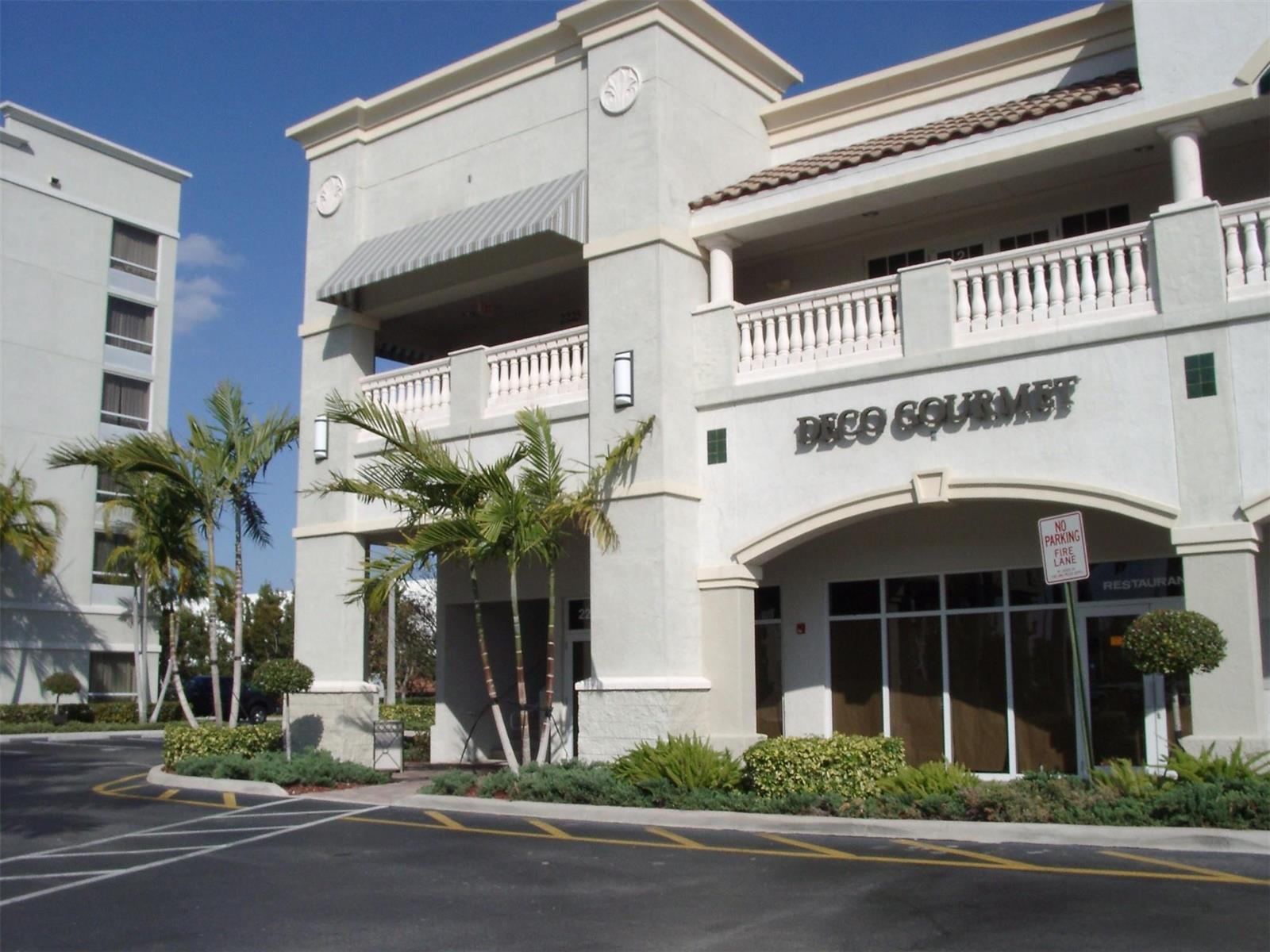 A two-story commercial building with a beige stucco facade, palm trees, and a parking lot — 2225 N Commerce Parkway # 7, Weston FL 33326, WESTON, FL