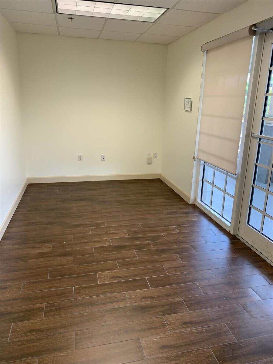 An empty office space features wood-look tile flooring, white walls, and a glass-paned door — 2225 N Commerce Parkway # 7, Weston FL 33326, WESTON, FL