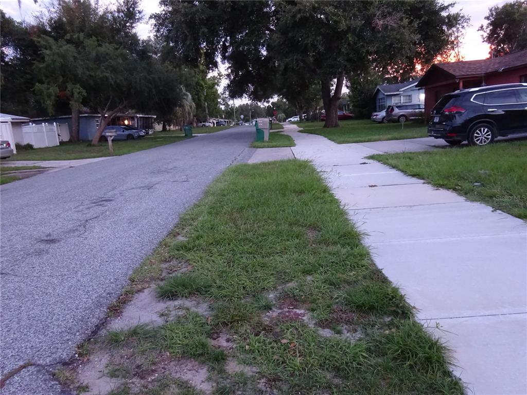 A residential street view featuring a sidewalk, a grassy verge, and parked cars — 6141 10TH STREET, ZEPHYRHILLS, FL