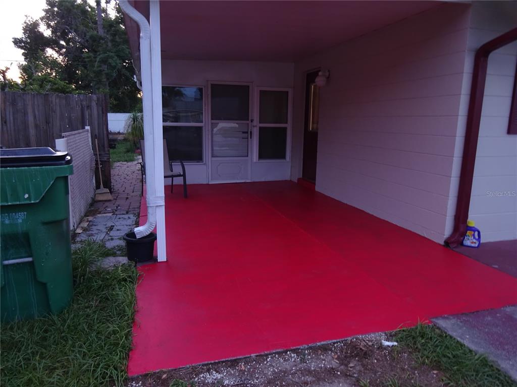 A covered concrete patio painted bright red sits adjacent to a house exterior — 6141 10TH STREET, ZEPHYRHILLS, FL