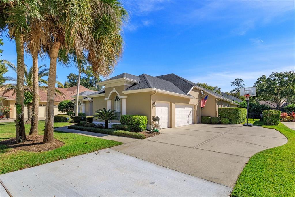 A tan house with a two-car garage, a concrete driveway, and palm trees in front — 5341 FAWN WOODS COURT, SANFORD, FL