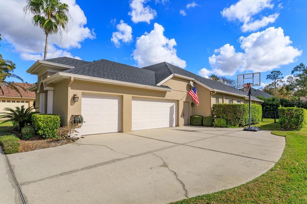 A tan house with a two-car garage, a concrete driveway, and an American flag — 5341 FAWN WOODS COURT, SANFORD, FL