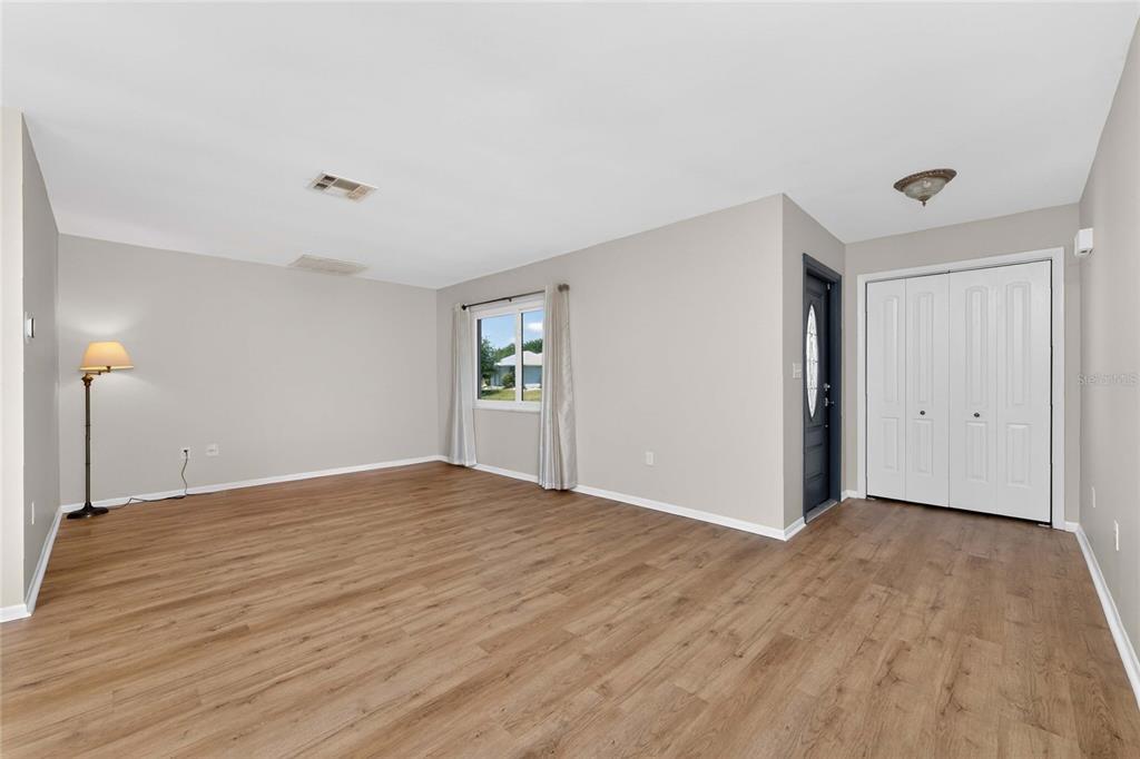 A living room with light gray walls, wood-look flooring, a window, and a closet — 557 MAGNOLIA AVENUE NW, PORT CHARLOTTE, FL