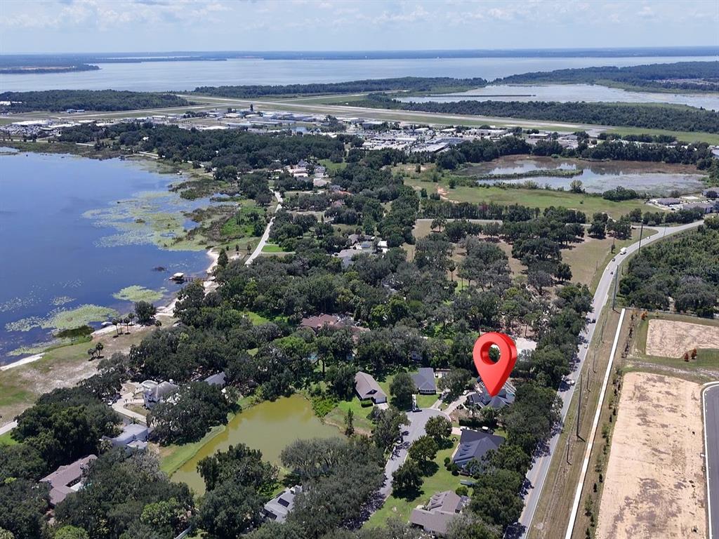 An aerial view shows a residential neighborhood with a lake, trees, and a red location pin — 33721 SPRING DRIVE, LEESBURG, FL