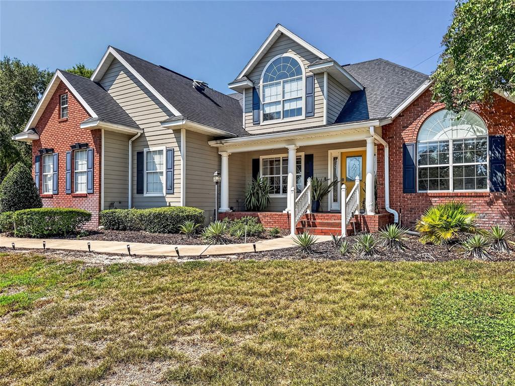 A two-story house features a brick and siding exterior with a covered front porch — 33721 SPRING DRIVE, LEESBURG, FL
