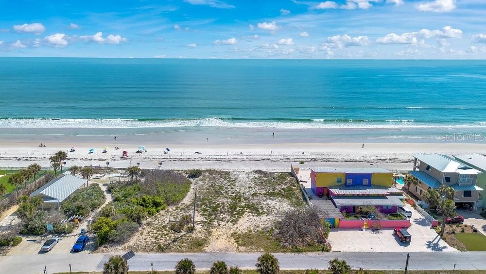 An aerial view shows a vacant beachfront lot between two houses and the ocean — 4591 S ATLANTIC AVENUE, PORT ORANGE, FL