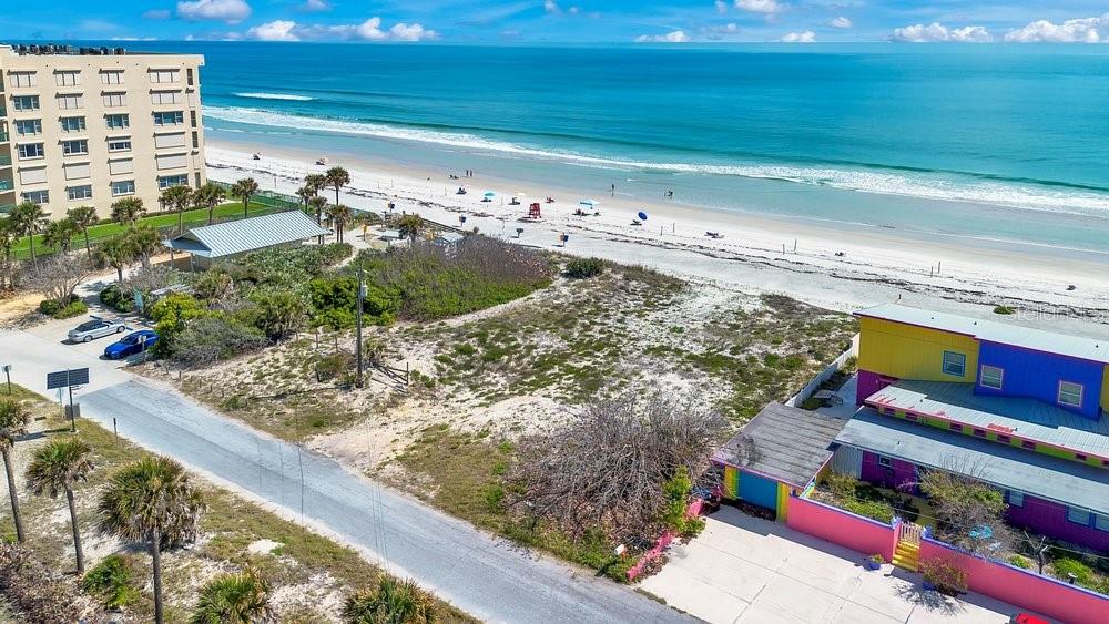 An aerial view shows a beach, a multi-story building, and a colorful house with landscaping — 4591 S ATLANTIC AVENUE, PORT ORANGE, FL