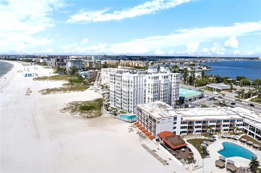 An aerial view of a white sand beach, coastal condominiums, and a swimming pool — 4950 GULF BOULEVARD UNIT 408, ST PETE BEACH, FL
