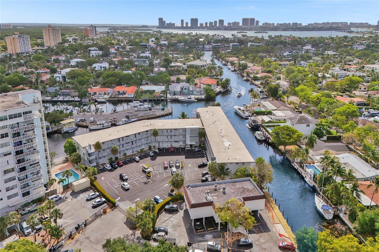 An aerial view shows a multi-story apartment complex with a parking lot and canal — 13105 Ixora Ct # 319, North Miami FL 33181, NORTH MIAMI, FL
