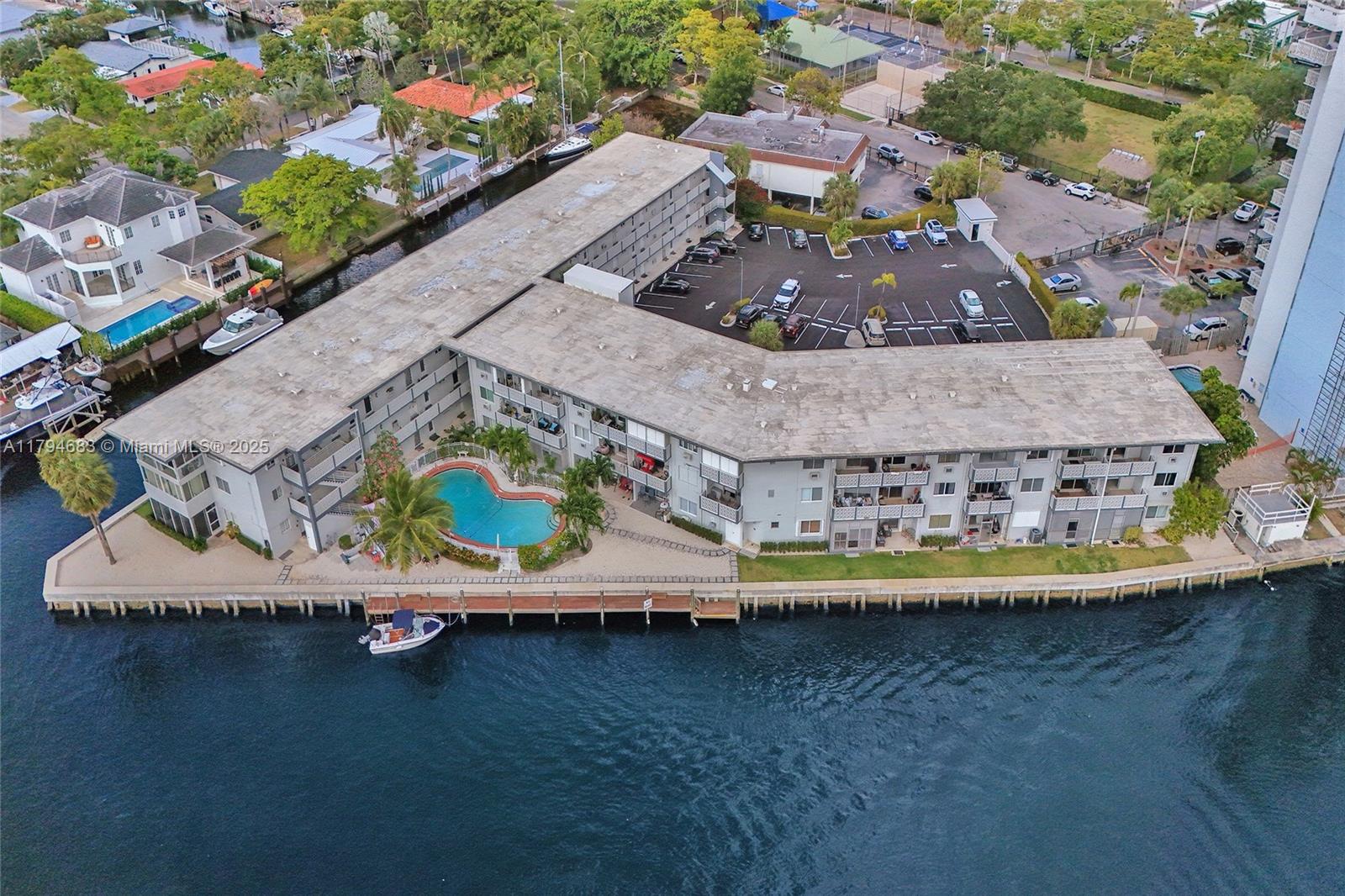 An aerial view shows an L-shaped apartment building with a pool, parking lot, and dock — 13105 Ixora Ct # 319, North Miami FL 33181, NORTH MIAMI, FL