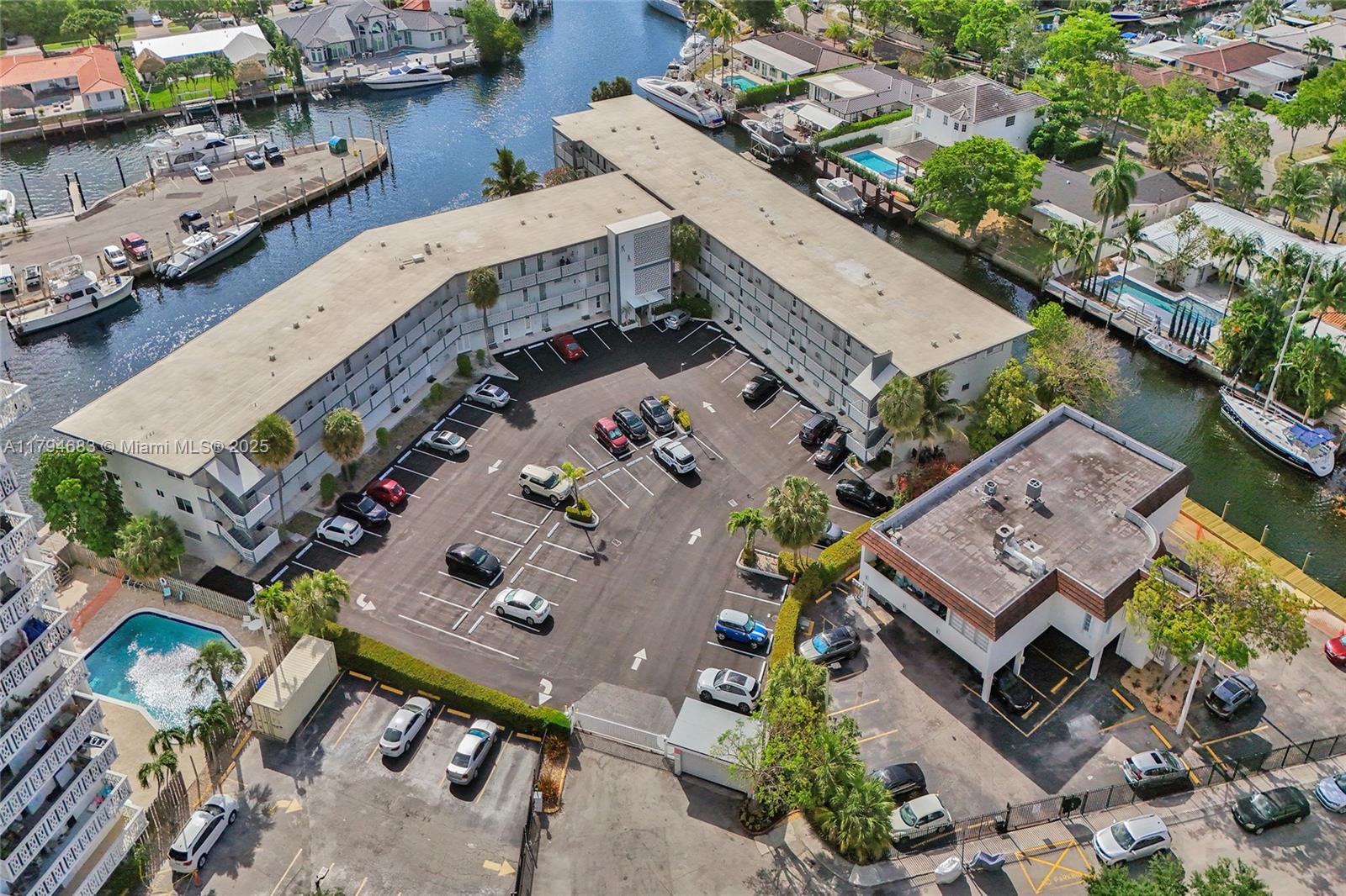 An aerial view shows a multi-story apartment building with a central parking lot and canal — 13105 Ixora Ct # 319, North Miami FL 33181, NORTH MIAMI, FL