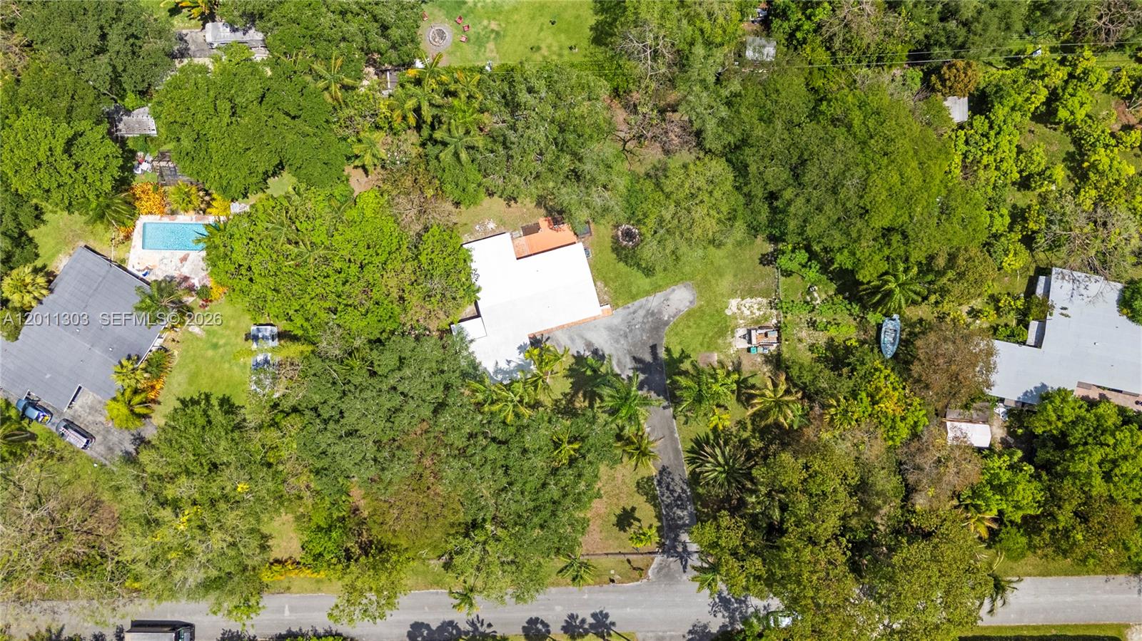 An aerial view shows a house with a white roof surrounded by lush green trees — 15345 SW 269th Ter, Homestead FL 33032, HOMESTEAD, FL
