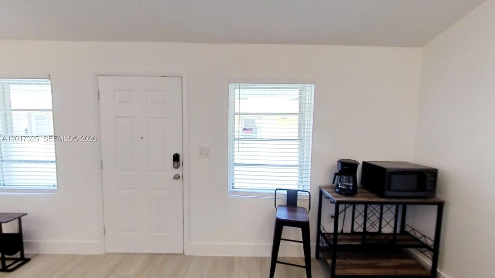 A white room features a door, a window with blinds, and a metal kitchen cart — 840 SW 7th St # 852, Miami FL 33130, MIAMI, FL
