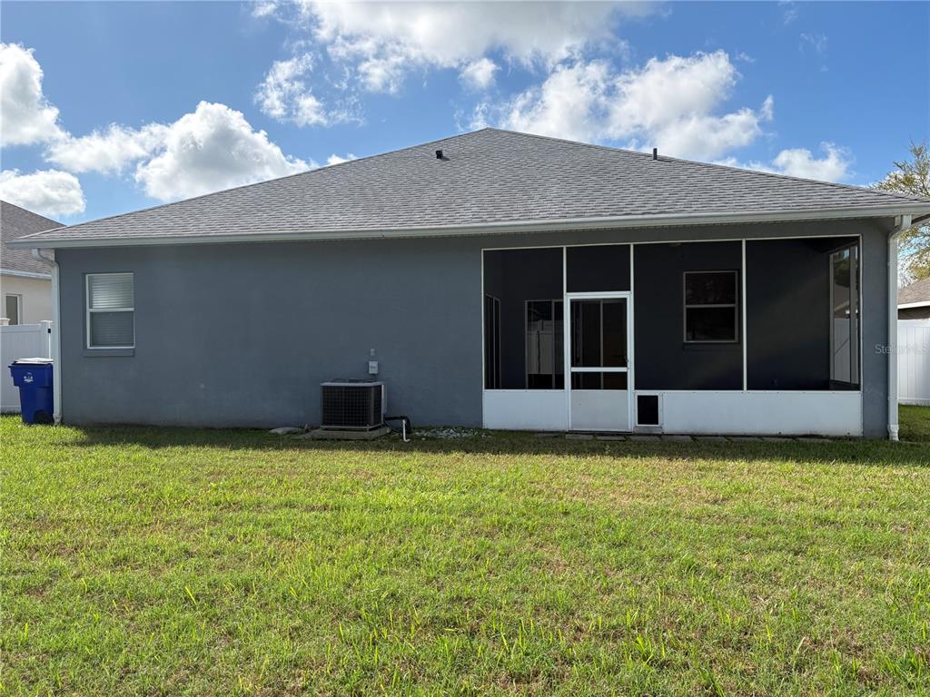 The exterior of a gray house features a screened-in porch and an air conditioning unit — 1150 CREEKVIEW, ST CLOUD, FL
