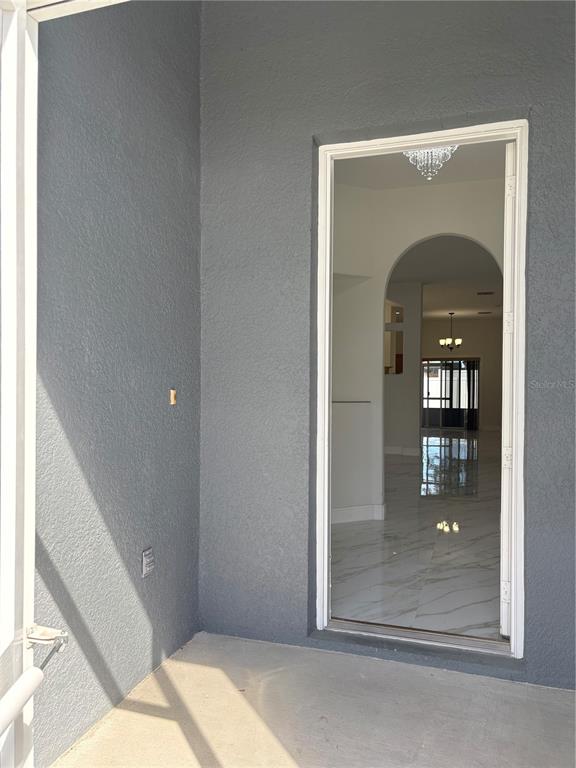 A view from a covered patio looking through an open doorway into a tiled interior — 1150 CREEKVIEW, ST CLOUD, FL