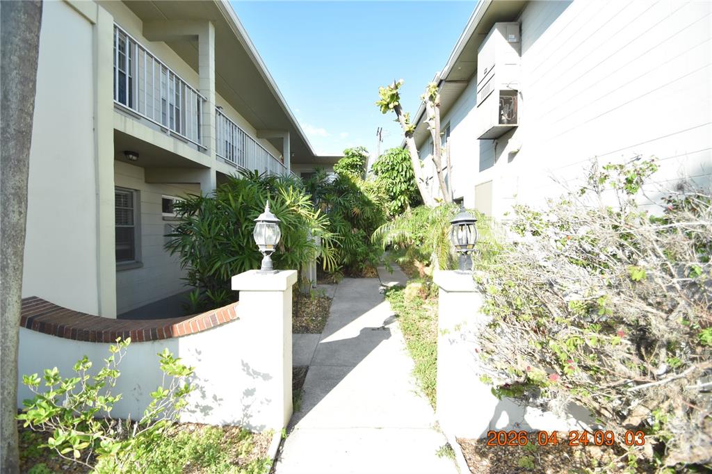 A concrete walkway leads between two apartment buildings with balconies and landscaping — 306 DANUBE AVENUE UNIT 2, TAMPA, FL