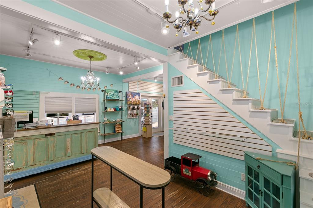 A retail space features turquoise walls, a wooden counter, a staircase with rope railings, and chandeliers — 135 4TH AVENUE N, SAFETY HARBOR, FL