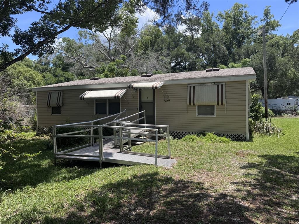 A single-story tan mobile home features a metal wheelchair ramp leading to the front entrance — 20050 RUTH STREET, BROOKSVILLE, FL