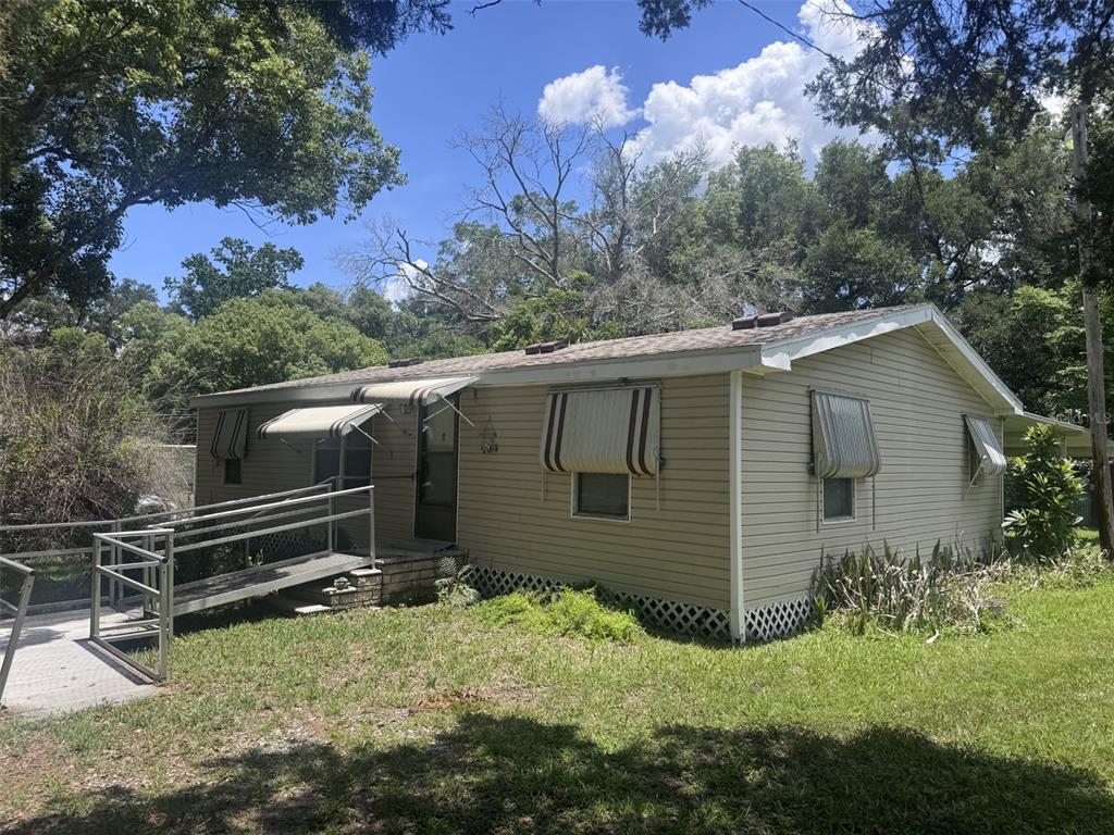 A single-story tan house with a metal wheelchair ramp leading to the front entrance — 20050 RUTH STREET, BROOKSVILLE, FL