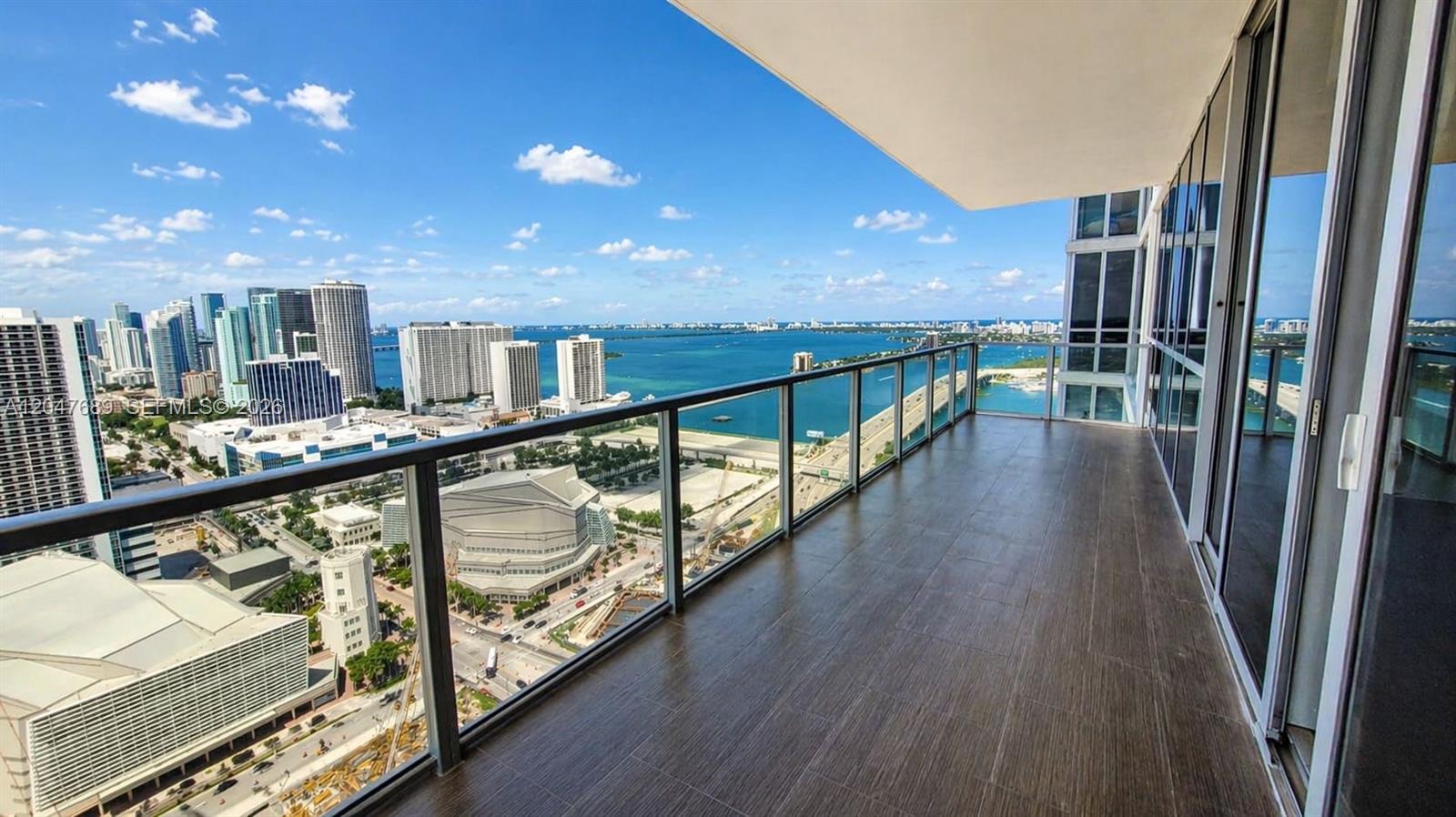 A high-rise balcony with dark wood-look tile flooring overlooks a city skyline and bay — 1100 Biscayne Blvd # 3708, Miami FL 33132, MIAMI, FL
