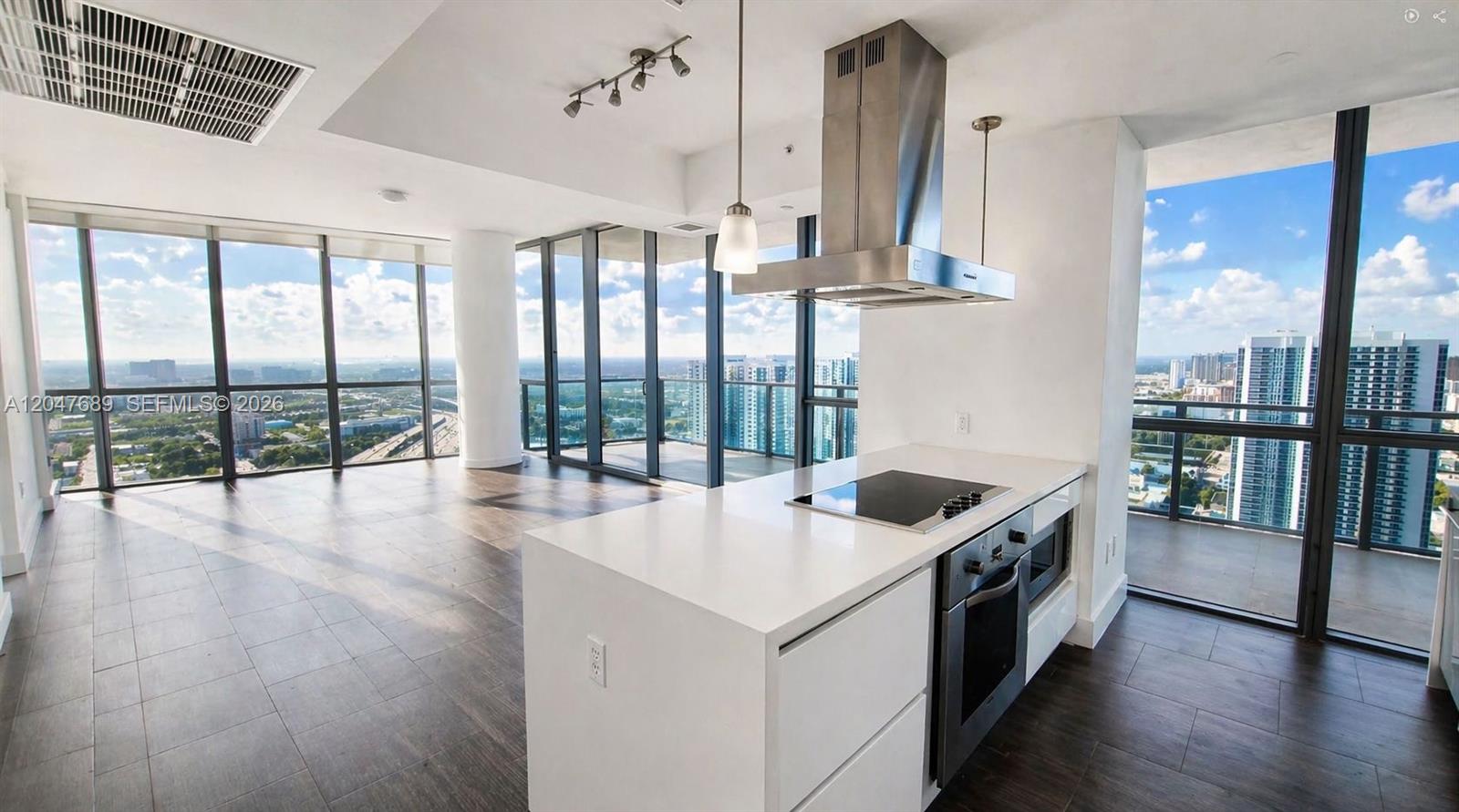 A modern kitchen island with a cooktop sits in an open-plan room with floor-to-ceiling windows — 1100 Biscayne Blvd # 3708, Miami FL 33132, MIAMI, FL