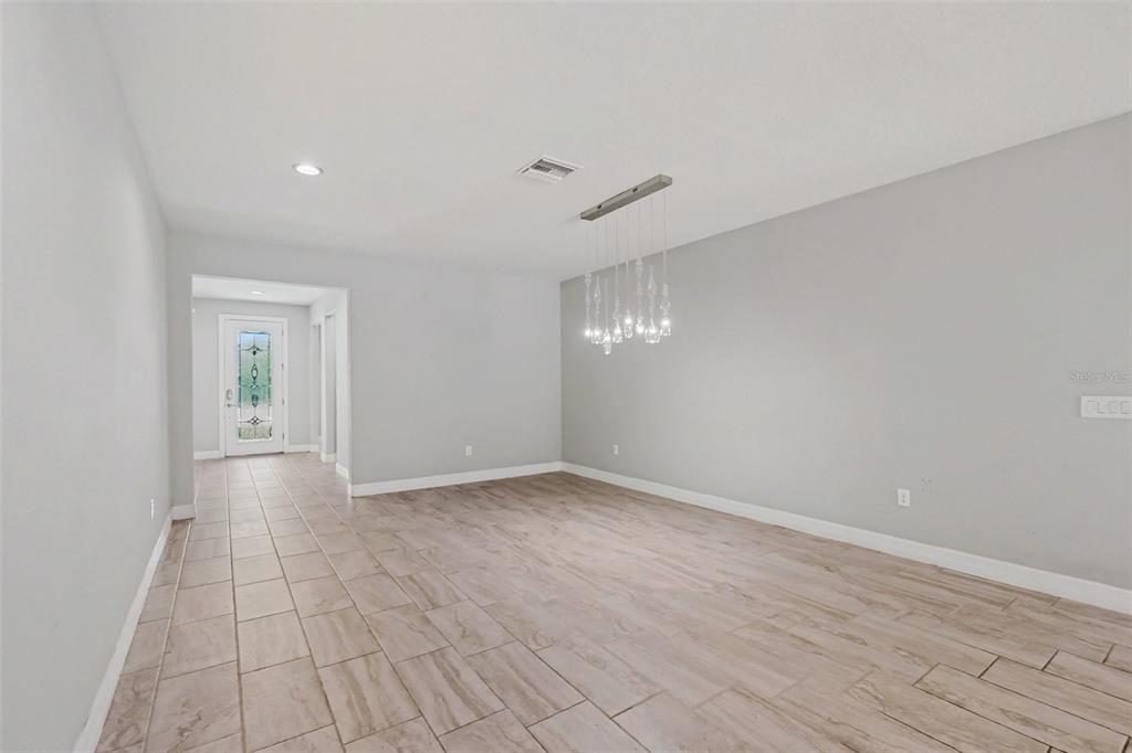A dining room with light gray walls, wood-look tile flooring, and a modern crystal chandelier — 11610 DUBLIN GRAFTON DRIVE, RIVERVIEW, FL
