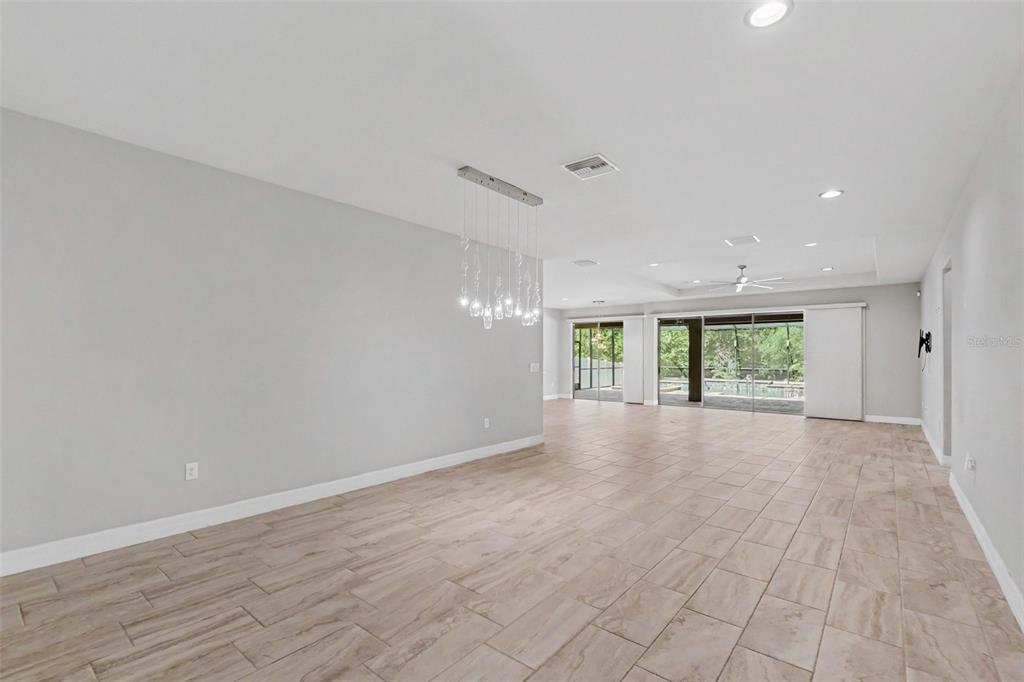 An open-concept living and dining area features light tile flooring, recessed lighting, and sliding doors — 11610 DUBLIN GRAFTON DRIVE, RIVERVIEW, FL