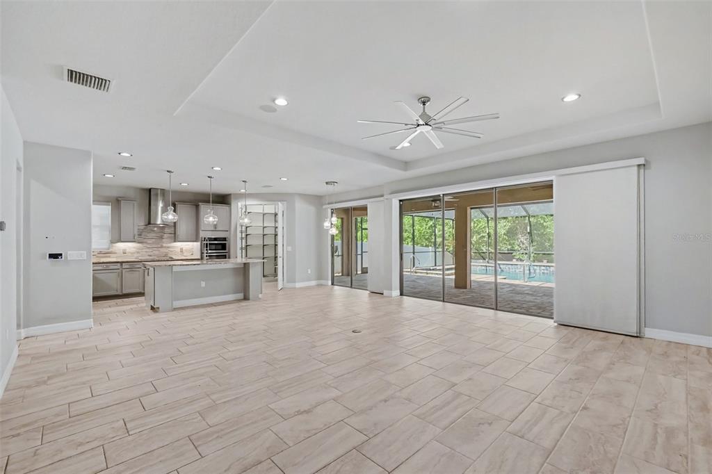 A spacious open-concept living area features light tile flooring, a modern kitchen, and sliding glass doors — 11610 DUBLIN GRAFTON DRIVE, RIVERVIEW, FL