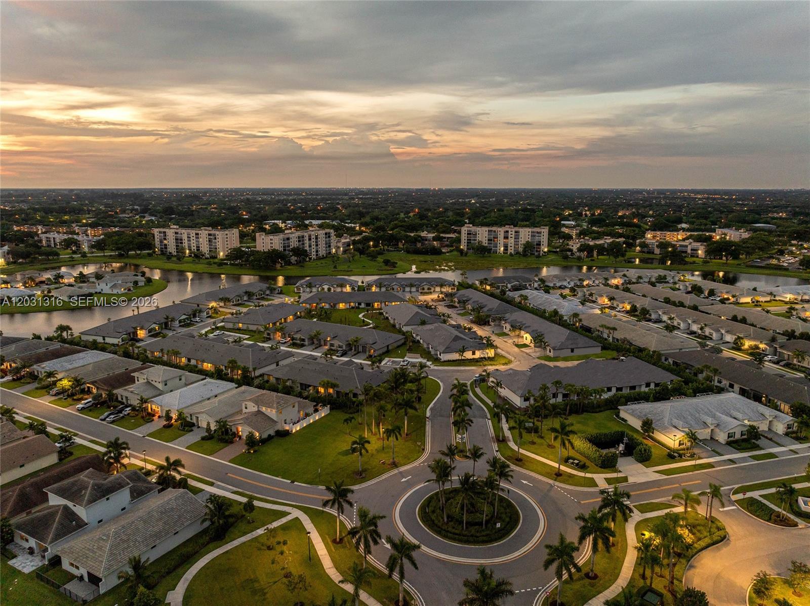 An aerial view shows a suburban residential neighborhood featuring a roundabout and a nearby lake — 7305 Ivory Spring, Delray Beach FL 33446, DELRAY BEACH, FL