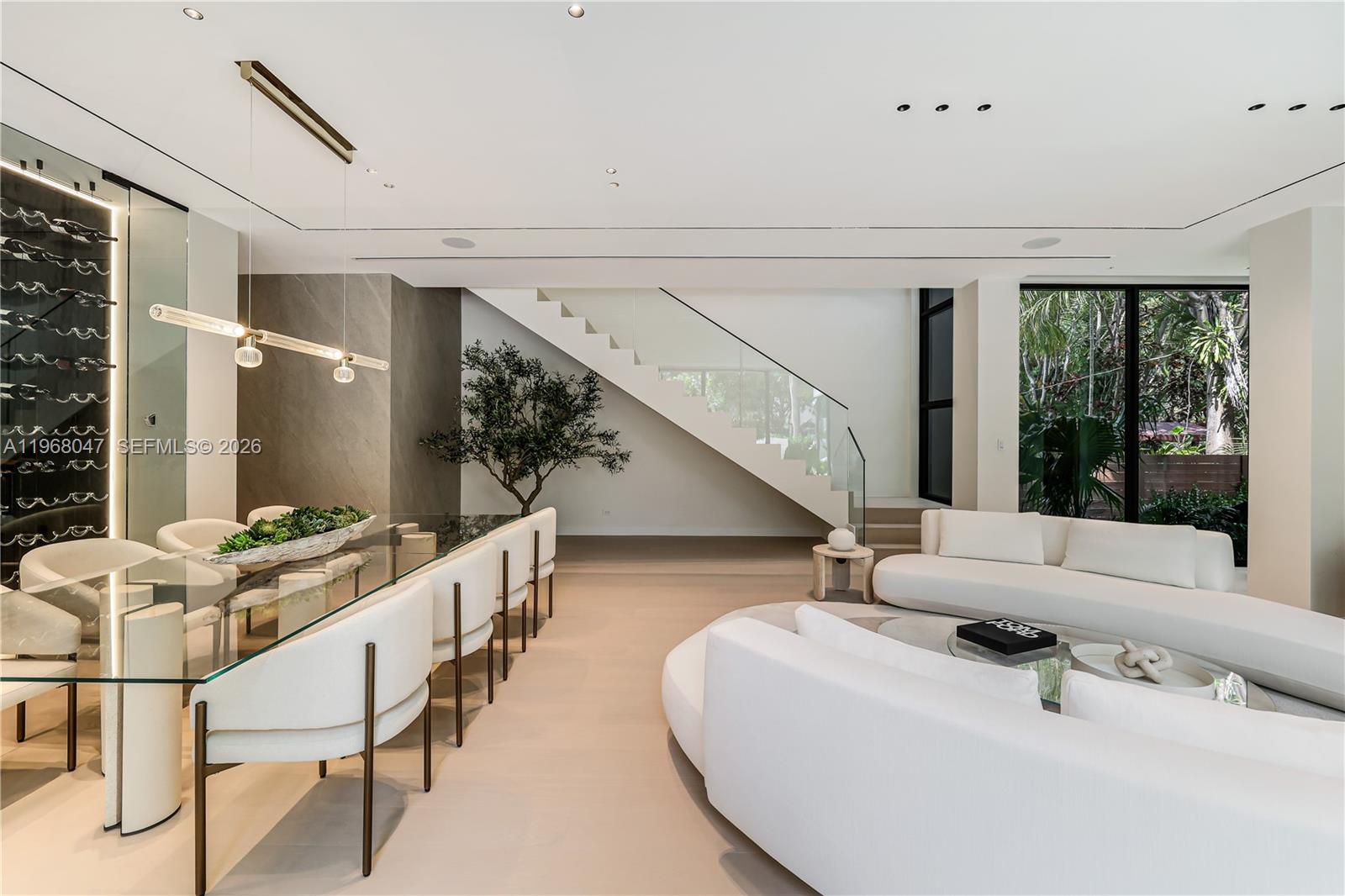 A modern open-concept living and dining area features white furniture, a glass staircase, and wine storage — 2497 Abaco Ave, Miami FL 33133, MIAMI, FL