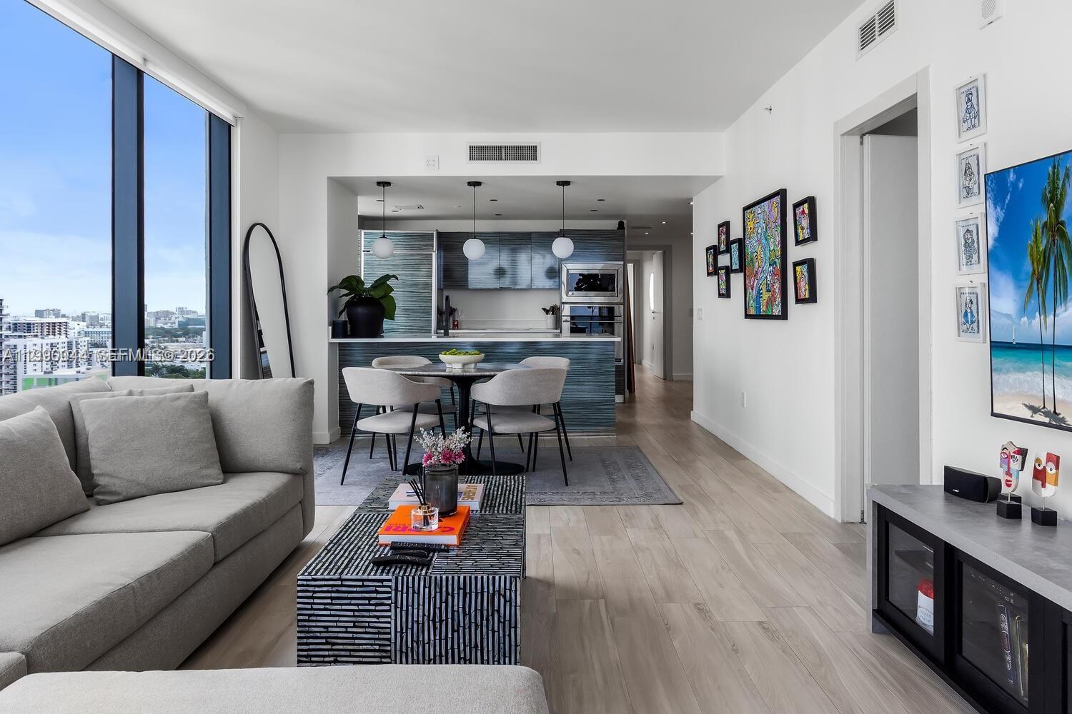 A modern living room and kitchen area with light wood floors and floor-to-ceiling windows — 460 NE 28th St # 2008, Miami FL 33137, MIAMI, FL