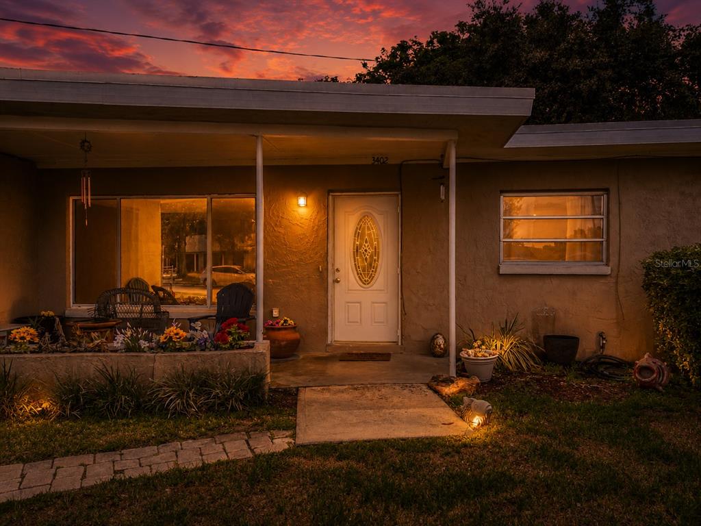 A single-story house exterior features a front porch, a white door, and a sunset sky — 3402 NEEDLES DRIVE, ORLANDO, FL