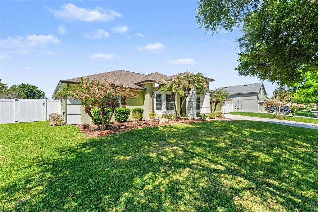 A single-story house with a light-colored exterior, a shingled roof, and a front lawn — 122 COSTA LOOP, AUBURNDALE, FL