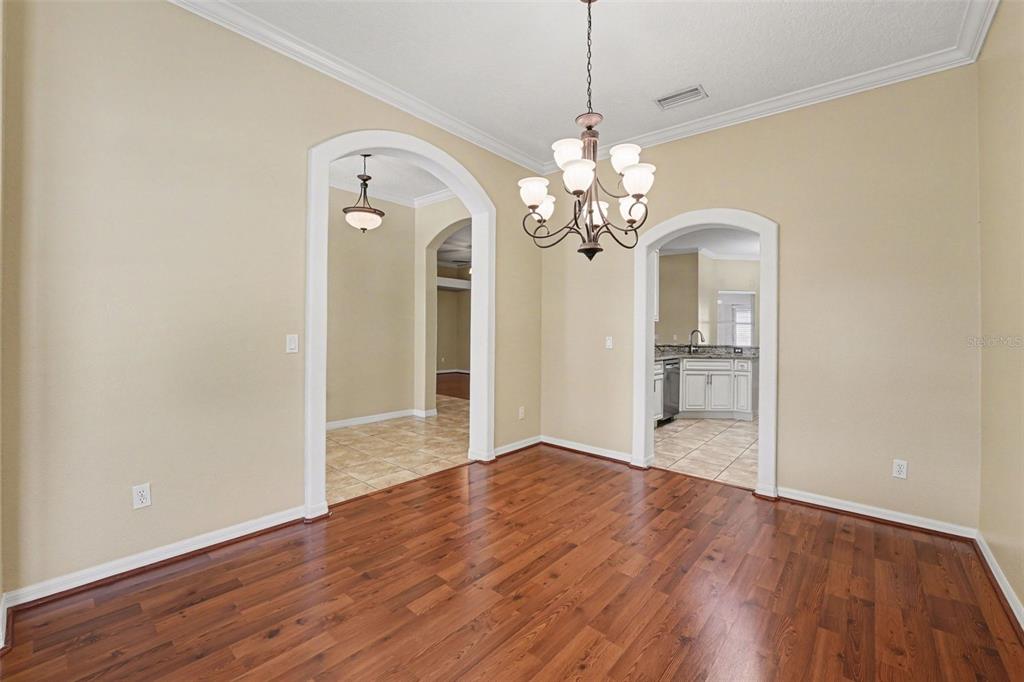 A dining room with hardwood floors, a chandelier, and arched doorways leading to other rooms — 122 COSTA LOOP, AUBURNDALE, FL
